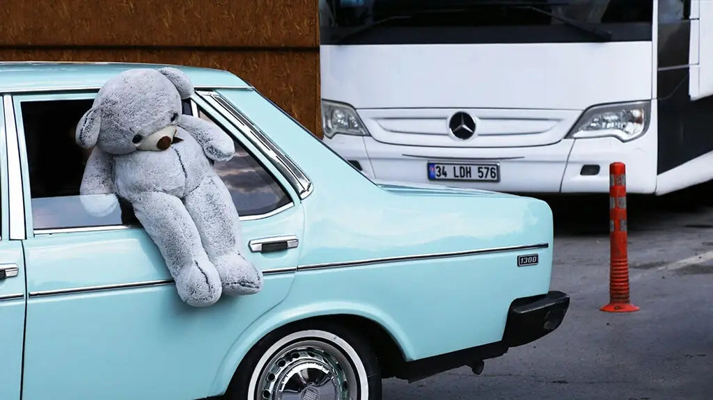 دمية دب قطيفة تجلس على نافذة السيارة