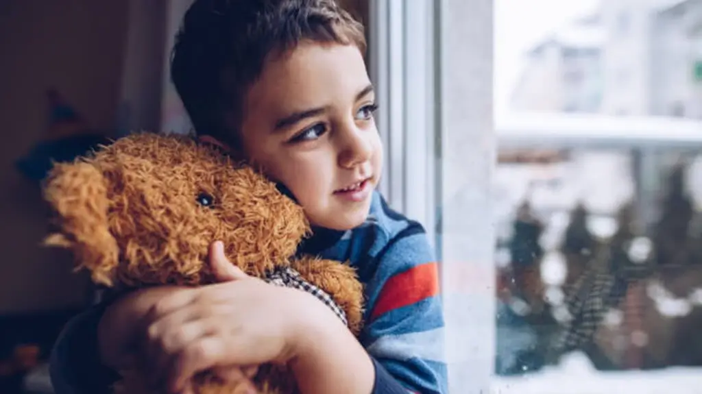 Little boy holding a bear plush toy