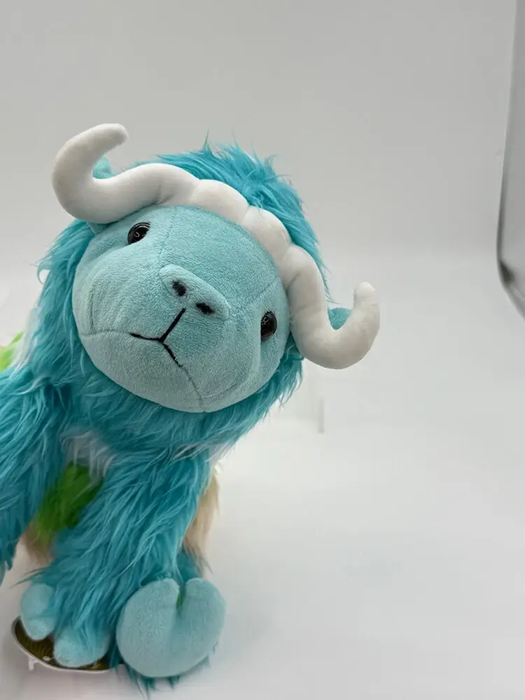 The mascot plush toy, a gradient sheep, mischievously looks at the camera.